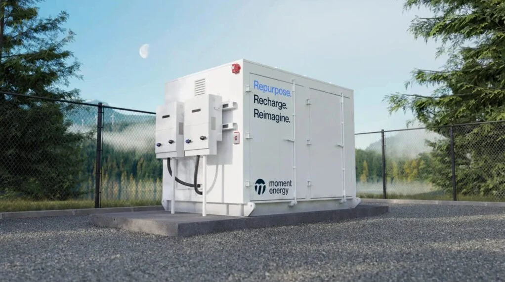 a battery energy storage unit painted white and bearing the moment energy logo stands alone and outside