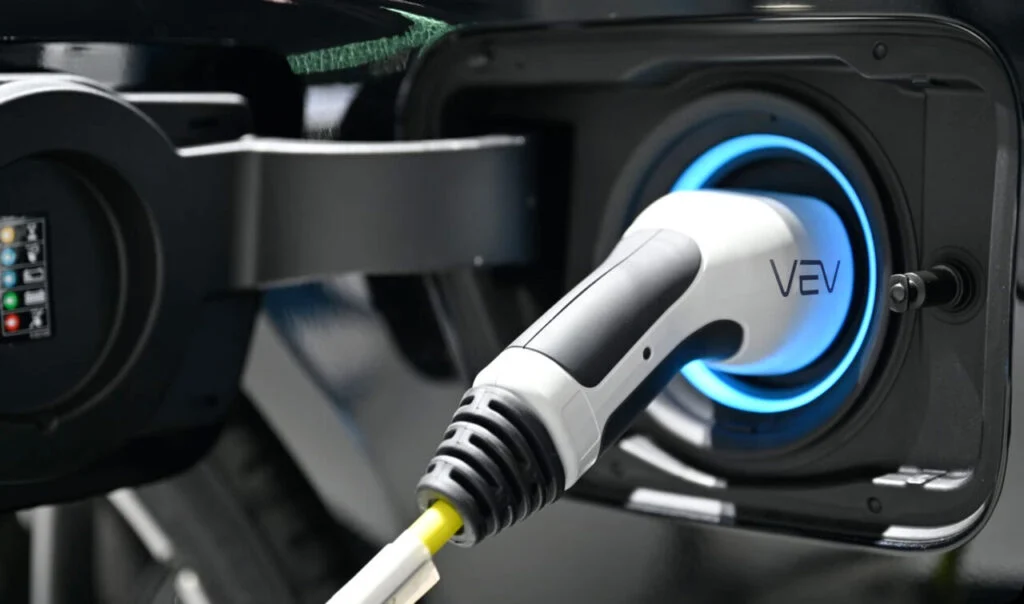 a VEV branded EV charger plugged into a vehicle, close up