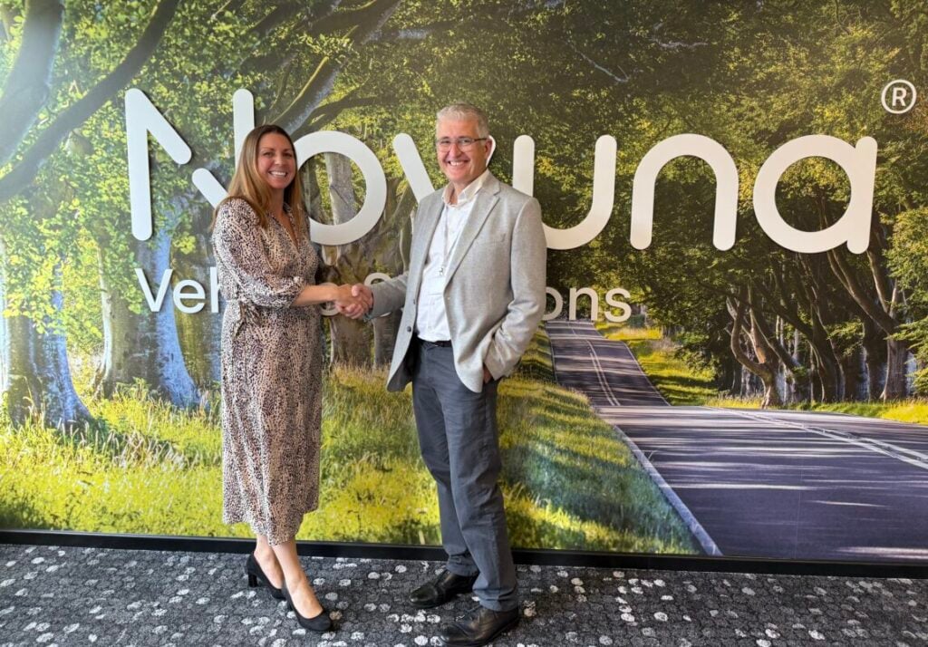 a white man and woman shake hands in front of the Novuna logo