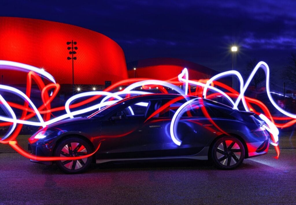 a car in a dark room with swirling neon waves of light surrounding it