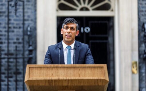 Rishi Sunak stands at a lectern in front of 10 Downing Street, drenched in rain