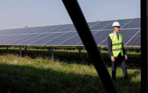 Ed Miliband walks next to solar panels in a hi ves vest and helmet