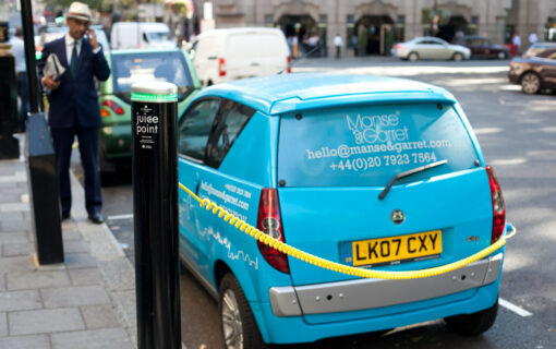 Recharging station for electric cars in London's Berkeley Square. For me, the bonus of the photo is the dapper gentleman with his newspaper speaking on the phone.