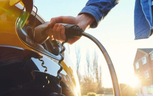 a hand plugging an ev charger into a car