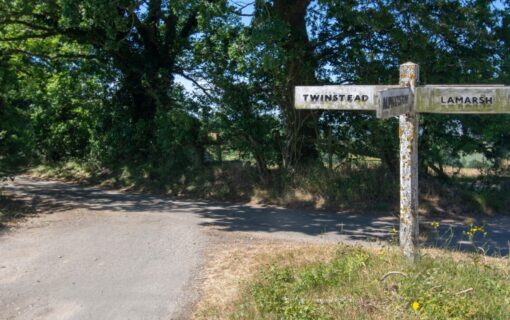 A country road with an old fashioned road sign pointing out the town of Twinstead
