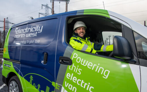 a man sits in an electricity north west branded van and smiles at the camera