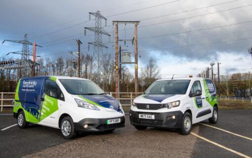 A pair of vans from the brand Electricity North West parked in front of electricity pylons.