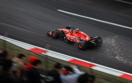 A red racing car on a track with sparks behind it
