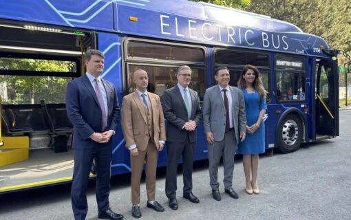 a group of people pose in front of a blue e-bus