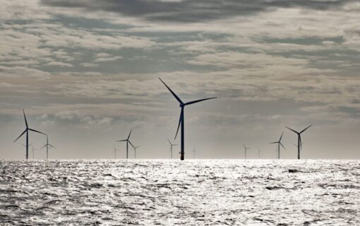 A collection of wind turbines sitting in a grey sea under a cloudy sky