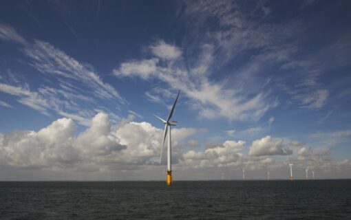 An offshore wind turbine underneath a blue sky with white clouds