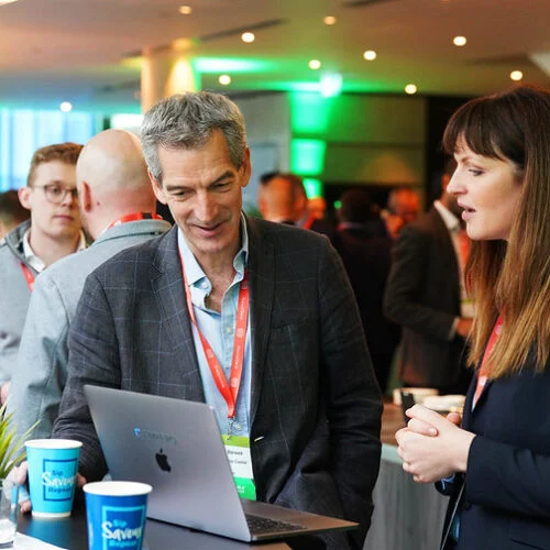 a man and a woman in business suits discuss business over a business laptop