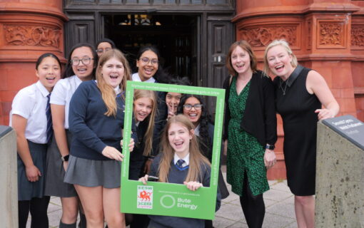 a group of schoolchildren smile and hold a frame with the bute energy logo