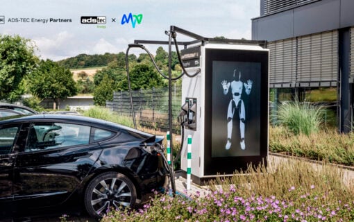 an ev charger with a large digital screen showing a robot, into which an EV is plugged