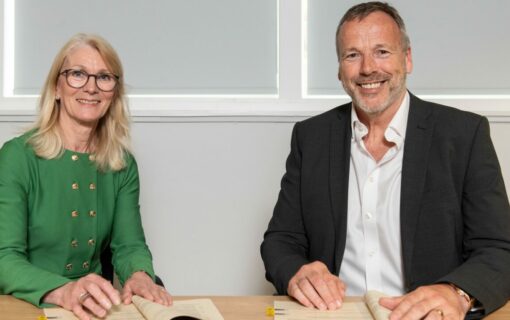 A woman and a man sit next to each other in business wear