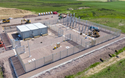 An electric substation viewed from above, surrounded by green fields