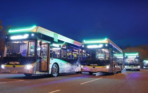 An image of two buses in the dark with lights on