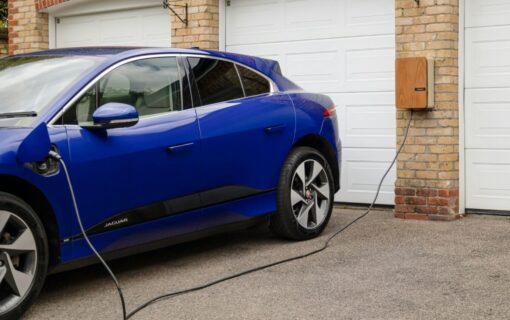 A blue car is plugged into a home EV charger