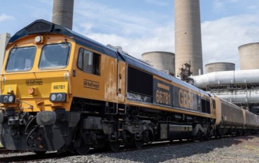 A freight train in front of a power station