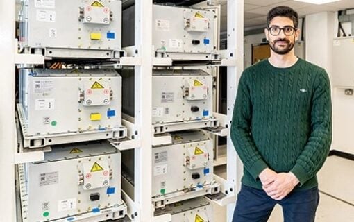 a man stands next to a rack of batteries