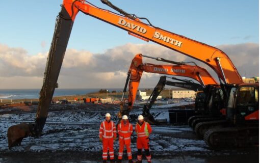 men in high vis stand in front of a digger on snowy ground