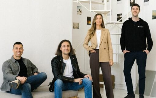 four smiling people are lined up in a row in a white room
