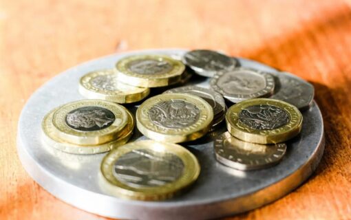 British coins of various denominations in a dish