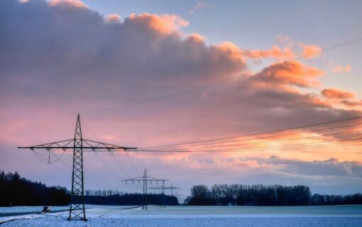 A pylon at sunrise in fields lightly dusted with snow