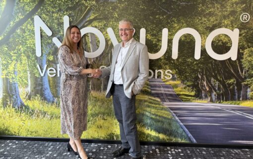 a white man and woman shake hands in front of the Novuna logo