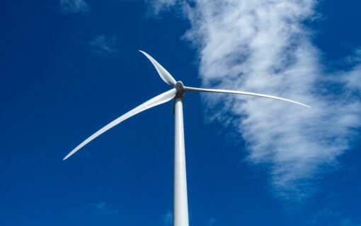 A single wind turbine in front of a bright blue sky