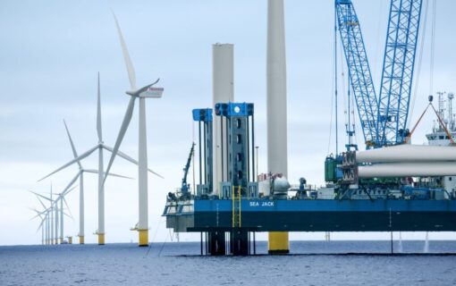 a platform in the ocean next to offshore wind turbines