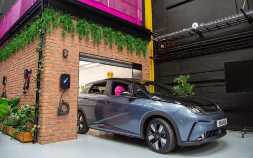 A car with a toy octopus in the window sits in a garage next to an EV charger in the Kraken Tech Centre.