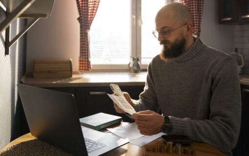 A man sat in front of his laptop looks at an energy bill and looks worried