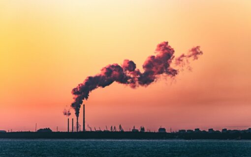 a smoke stack in the far distance at sunset