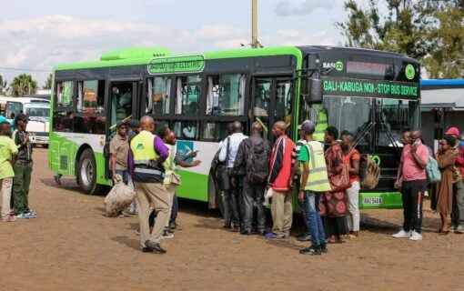 an electric bus surrounded by people on a warm dusty road
