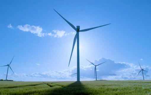 wind turbines in a green field under a blue sky