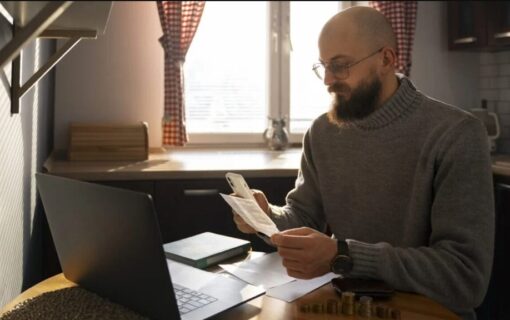 A man sat in front of his laptop looks at an energy bill and looks worried