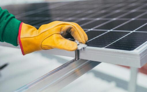 a hand in a yellow glove touches a solar panel