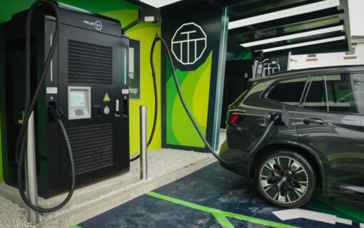 A lime green and black Ev charging station plugs into an electric car
