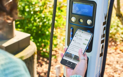 a person holds a smartphone up to an EV chargepoint