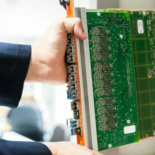 a pair of hands holds a large computer motherboard