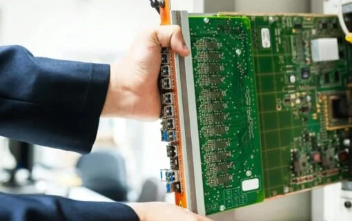 a pair of hands holds a large computer motherboard